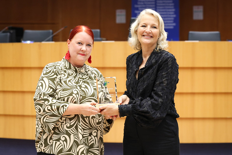 Kaksi ihmistä hymyilevät palkinnon kanssa.