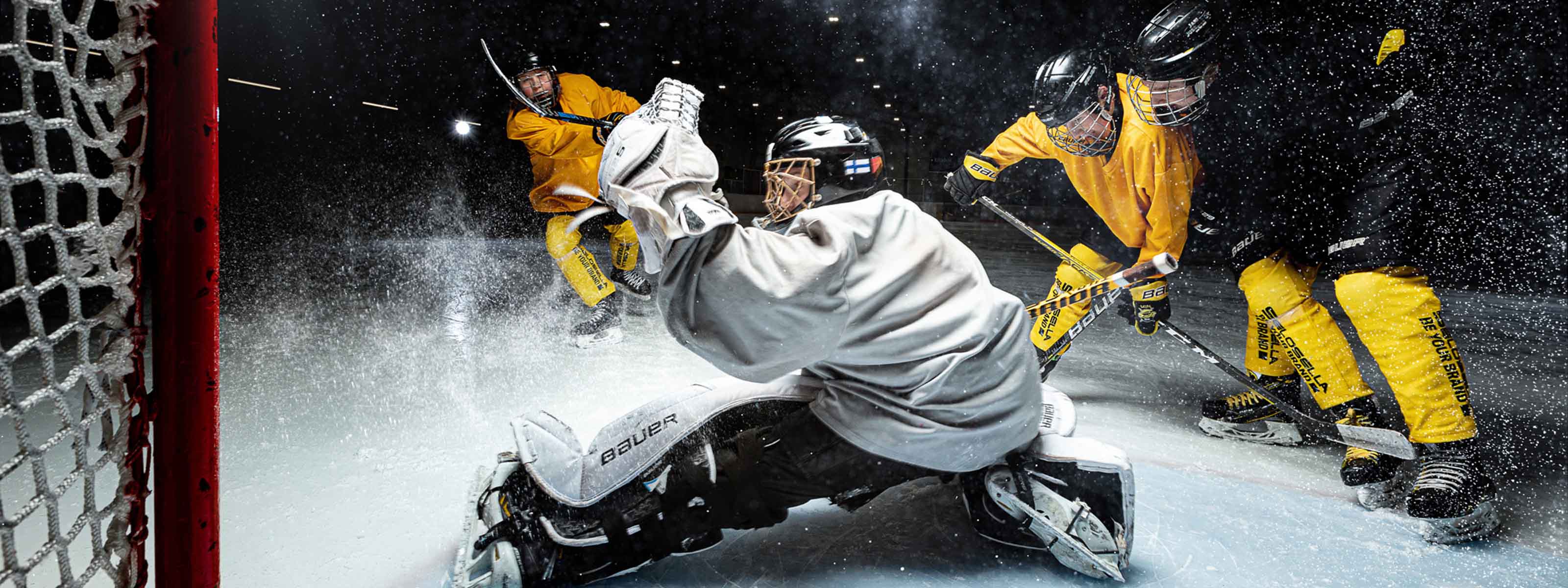 Neljä jääkiekkoiljaa ja jääkiekkomaali.