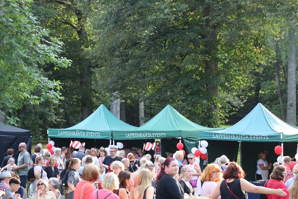 Väkijoukko puistossa, ihmisillä punavalkoiset vaatteet.