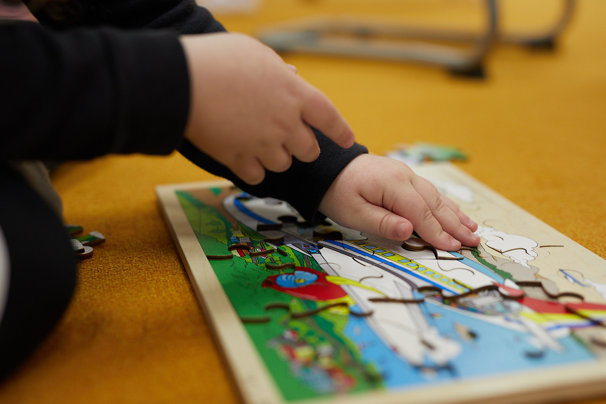 Lapsi kokoamassa palapeliä koululuokan lattialla.