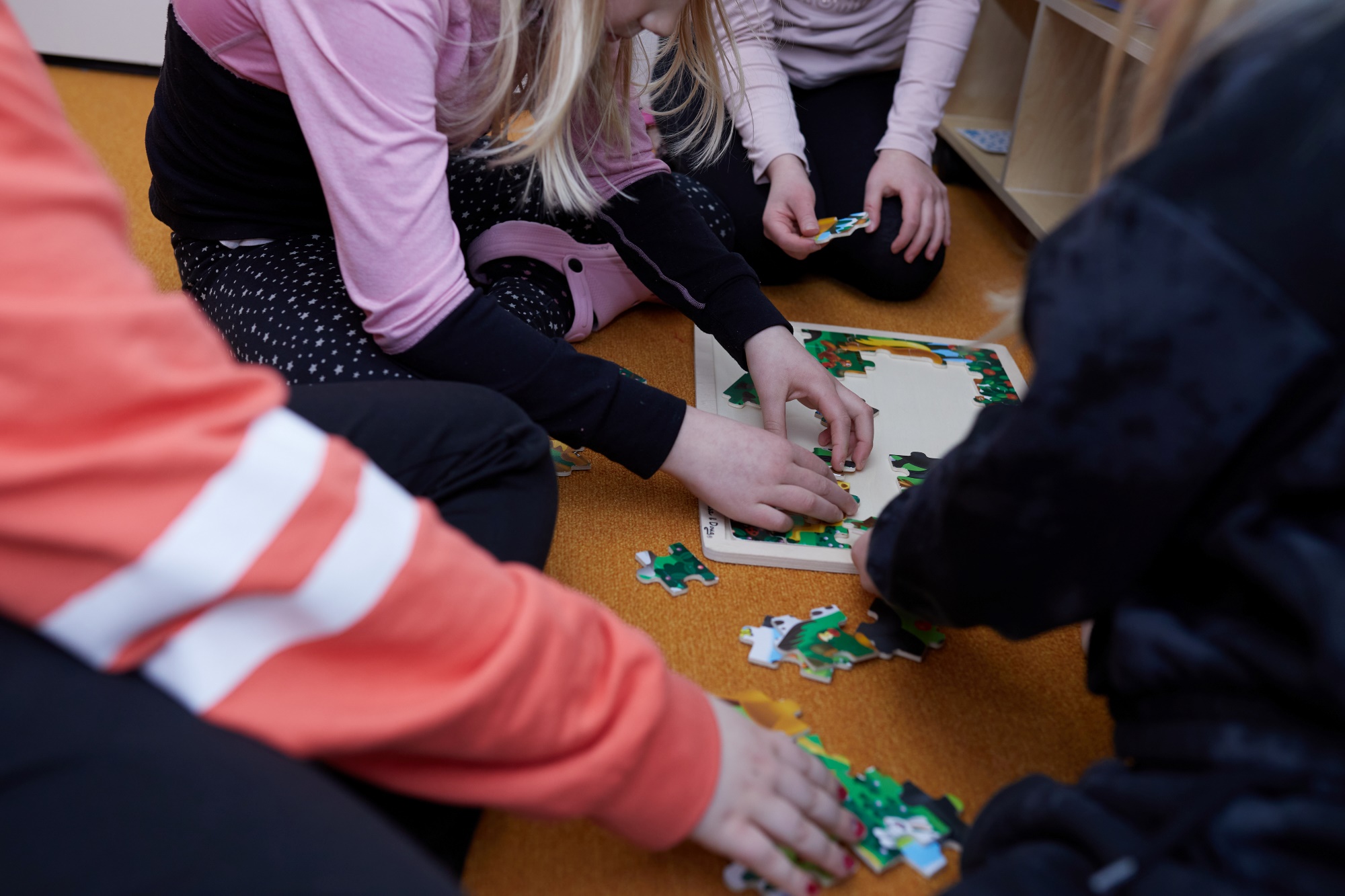 Oppilaita kokoontuneena kokoamaan palapeliä.