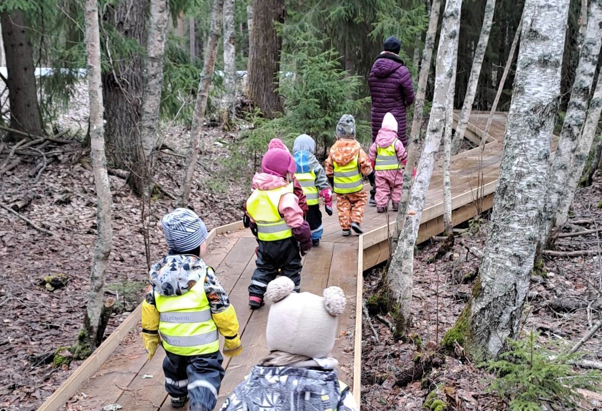 Heijastinliiveihin sonnustautunut varhaiskasvatusryhmä metsäretkellä.