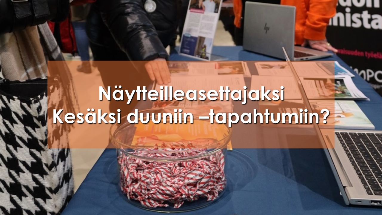 Messutapahtuman esittelypöytä, jossa esillä esitteitä, tietokone ja karkkeja.