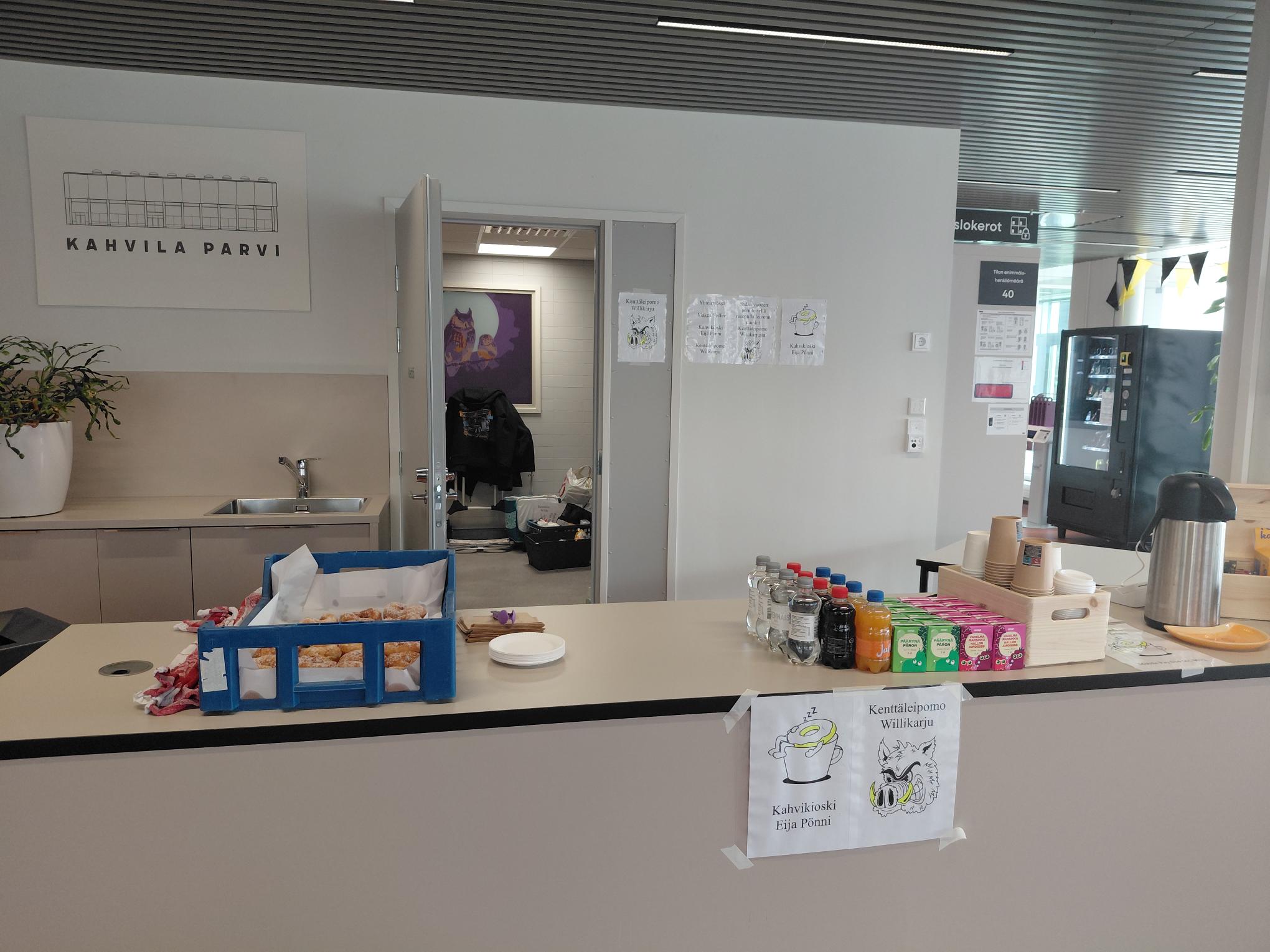 Lappeenrannan pääkirjaston kahvilatilan myyntitiski, johon on asetettu esille myytäviä leivonnaisia ja juomia.