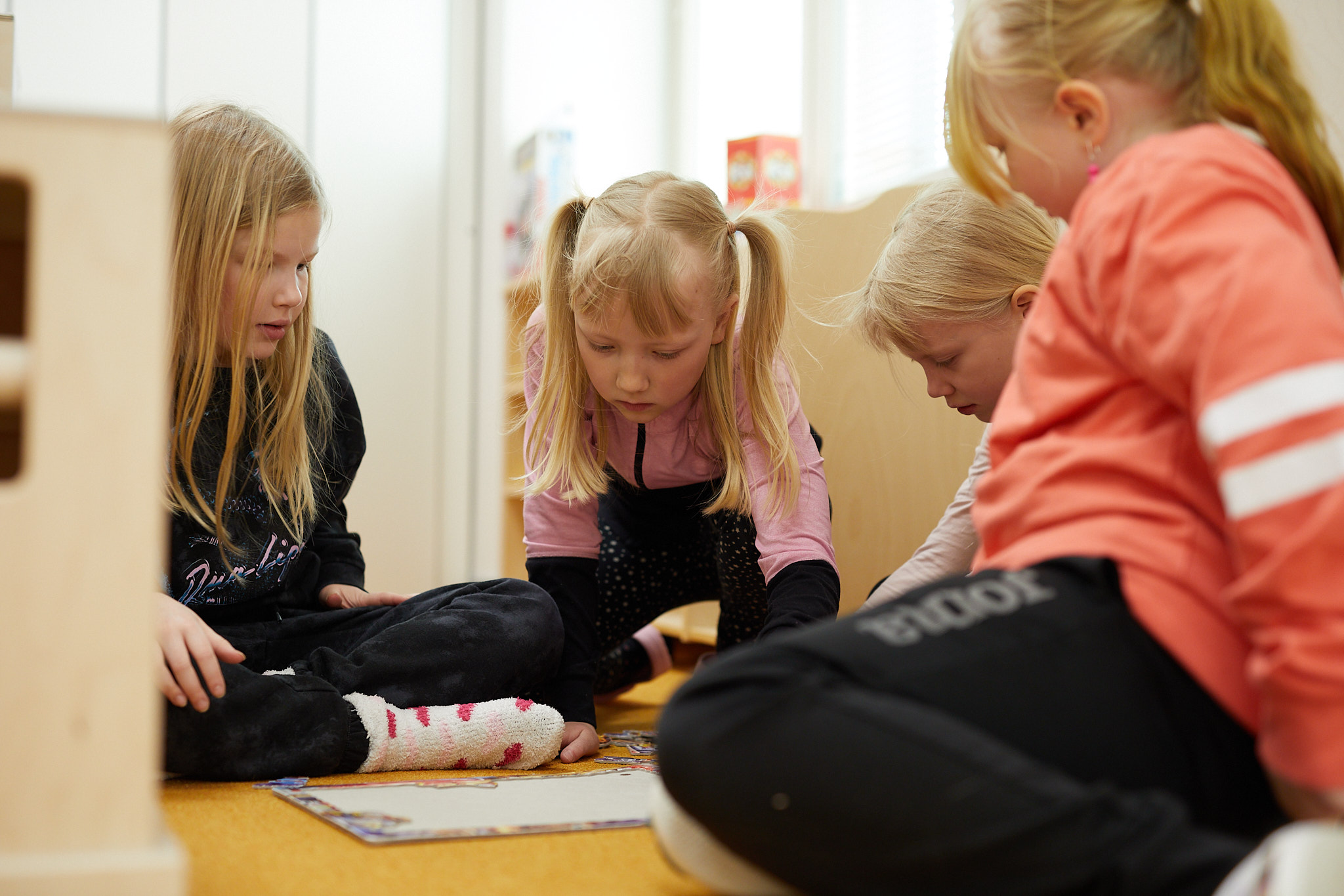 Koululaisia kokoamassa palapeliä luokkahuoneen lattialla istuen.