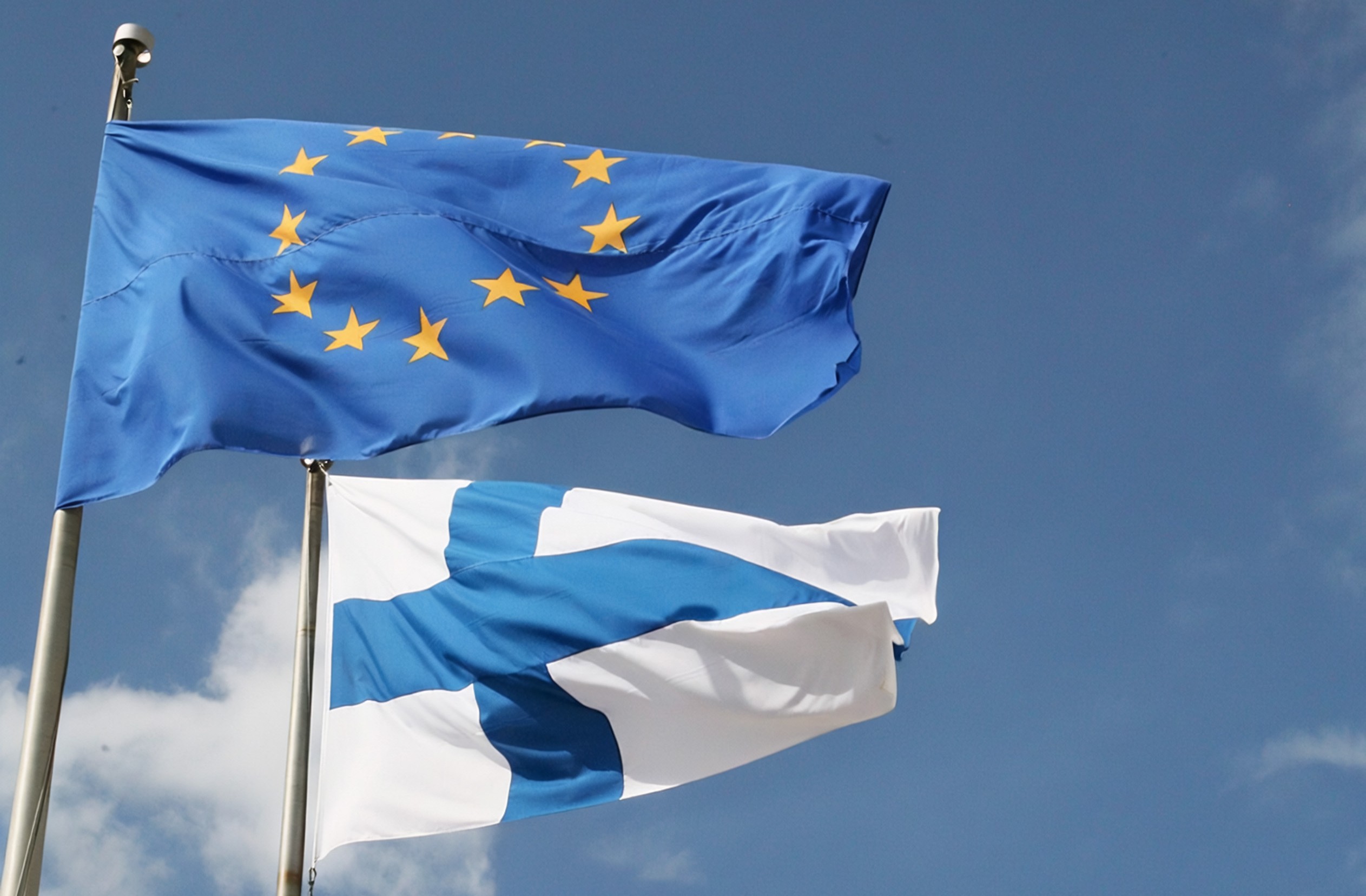 Suomen ja Euroopan unionin liput liehuvat saloissa.