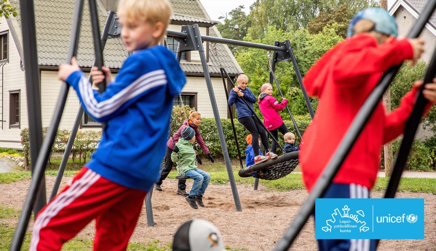 Lapsia leikkimässä ja keinumassa leikkipaikalla, Lappeenrannan logo sekä UNICEFin Lapsiystävällinen kunta -logo.