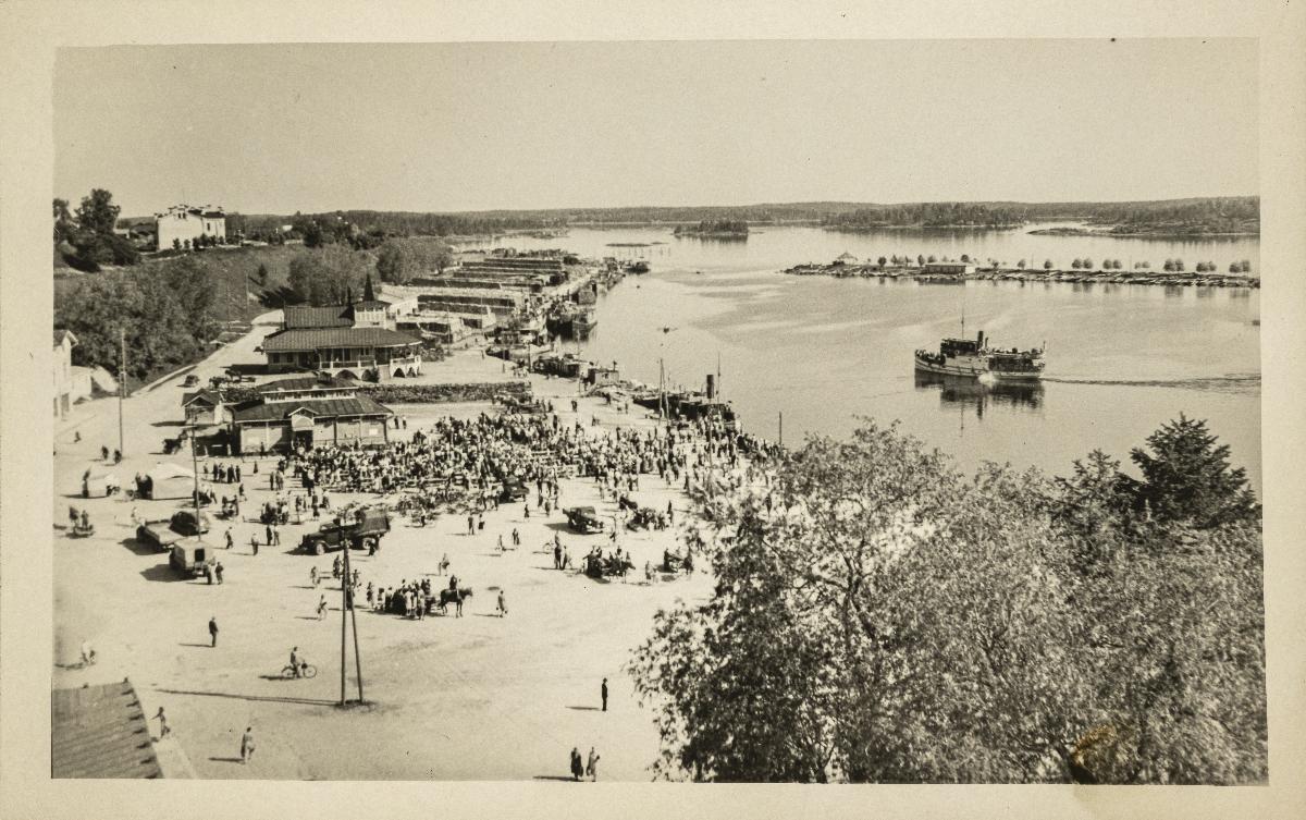 Mustavalkokuvassa Lappeenrannan satamatorilla ihmisiä sekä kaupunginlahti ja Halkosaari kuvan yläkulmassa. Kuva:Mortensen, 1952.