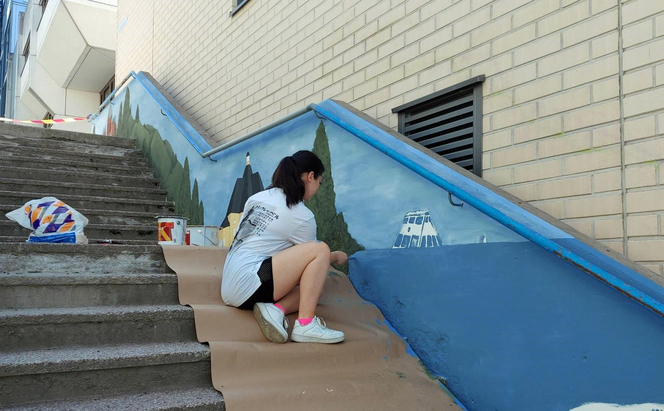 Nuori maalaamassa ulkoportaikkoa.